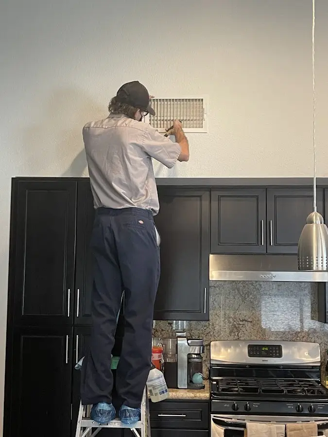 Technician inspecting an air vent during HVAC service in Millville